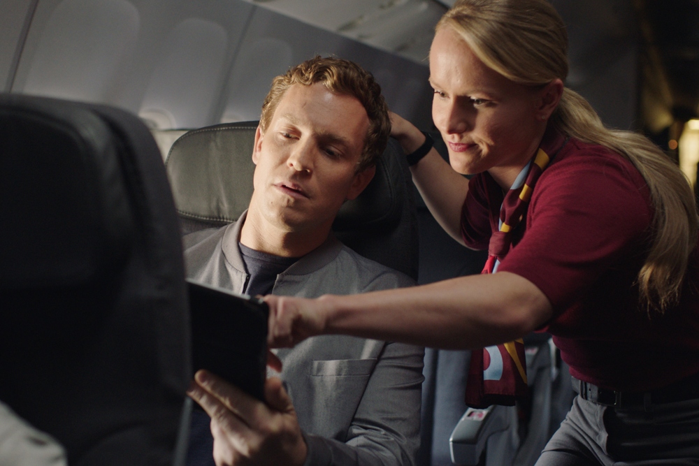 Un couple assis dans la section Rouge en train de se servir du système de divertissement lecteur en vol d’Air Canada Rouge.