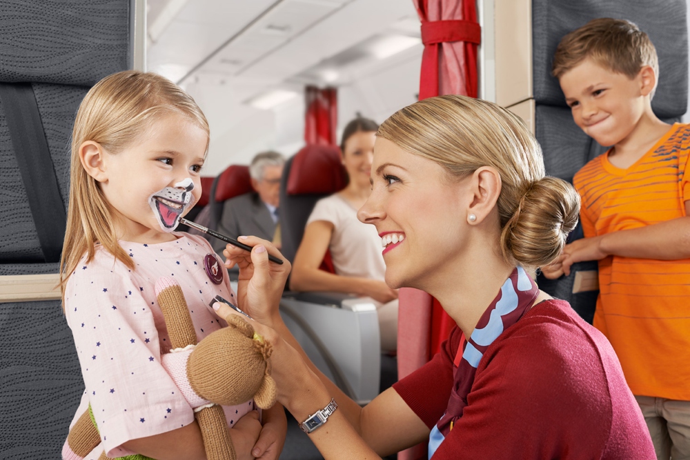 Un agent de bord d’Air Canada Rouge est en train de peindre le visage d’une enfant qui sourit.